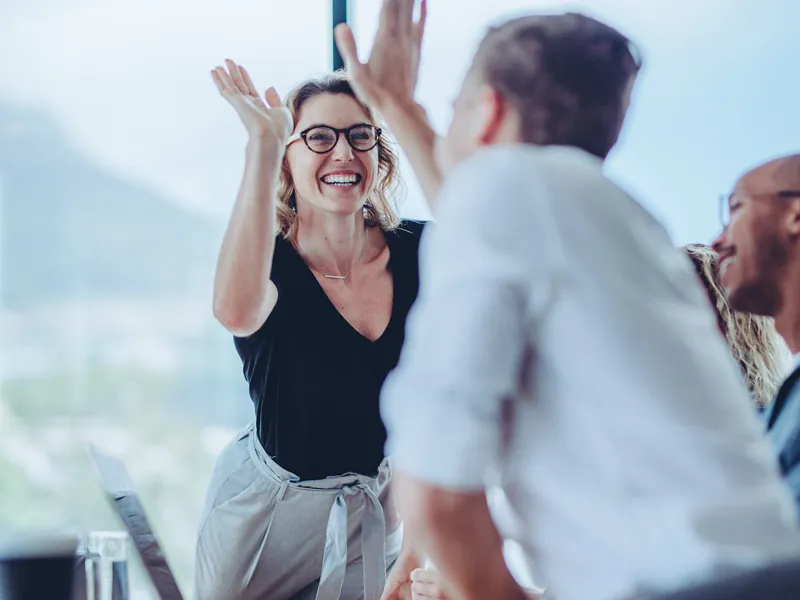 Freudiger High Five zwischen zwei Personen während eines erfolgreichen Business Meetings